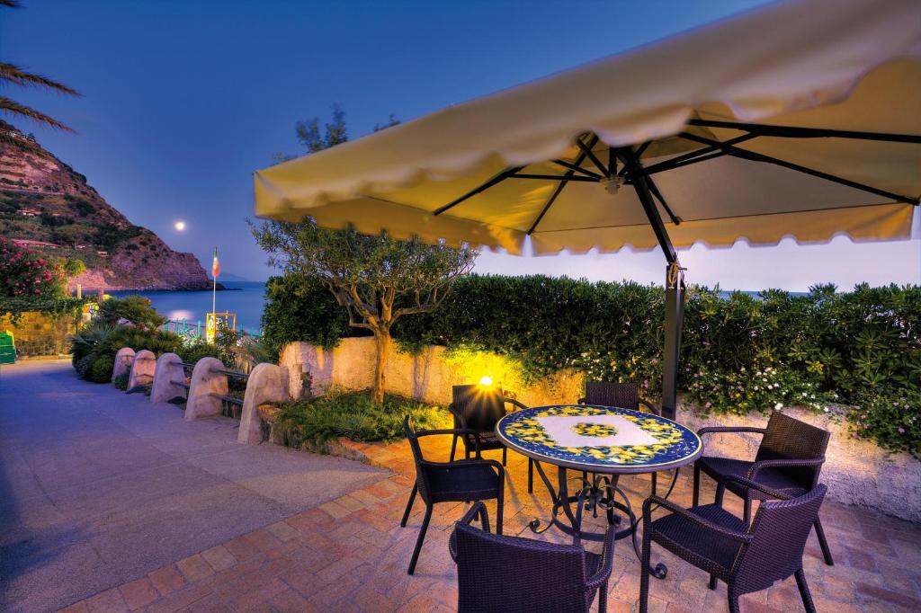 a patio with a table and chairs and an umbrella at Hotel Parco Smeraldo Terme in Ischia