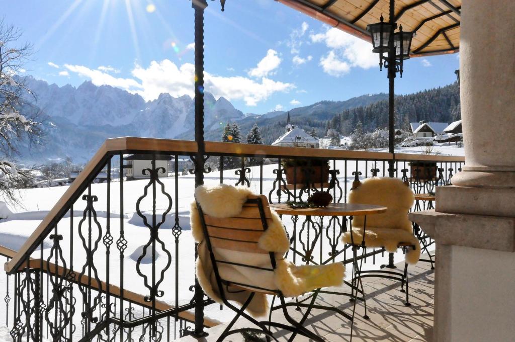 a table and chairs on a balcony with a view of mountains at Landhaus Koller in Gosau