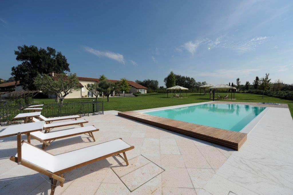 a swimming pool with benches and a group of chairs at Tenuta La Cà in Bardolino