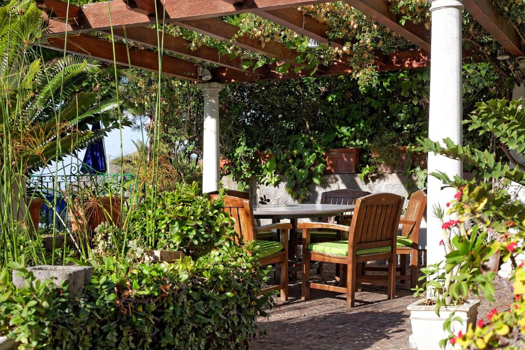 a patio with a table and chairs under a pergola at Hotel Parco Smeraldo Terme in Ischia