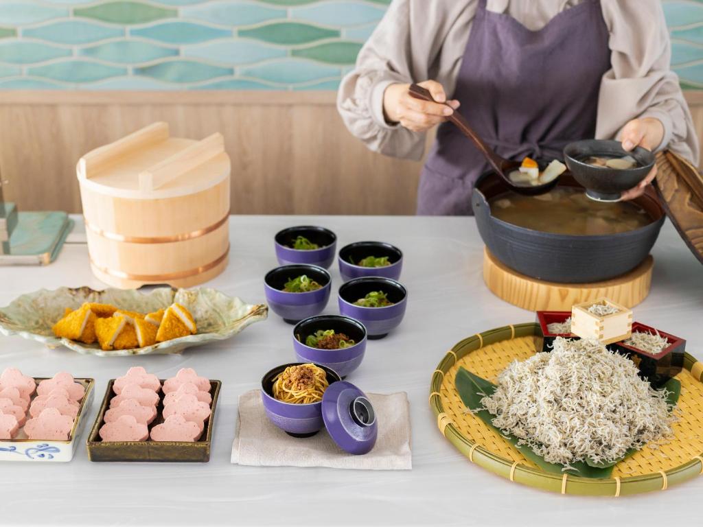 a person is preparing food on a table with food at Mitsui Garden Hotel Hiroshima in Hiroshima