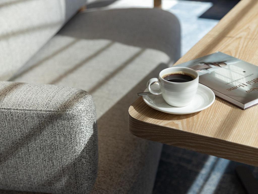 a cup of coffee and a book on a table at Mitsui Garden Hotel Hiroshima in Hiroshima