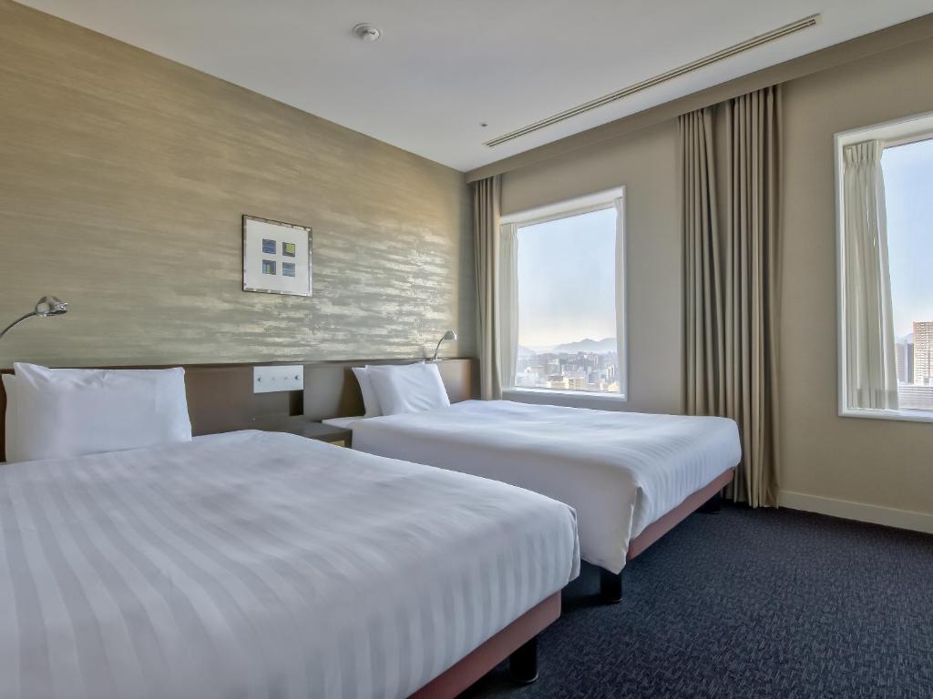 two beds in a hotel room with two windows at Mitsui Garden Hotel Hiroshima in Hiroshima