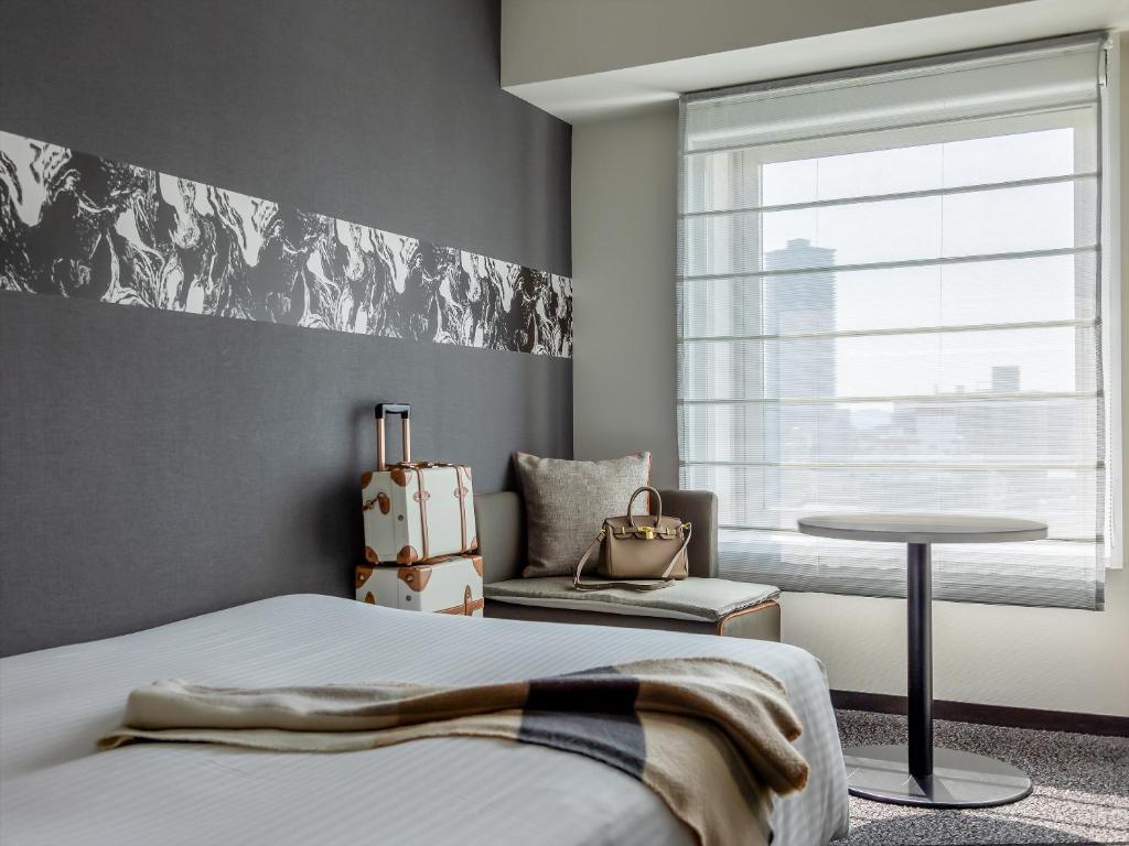 a bedroom with a bed and a table and a window at Mitsui Garden Hotel Hiroshima in Hiroshima
