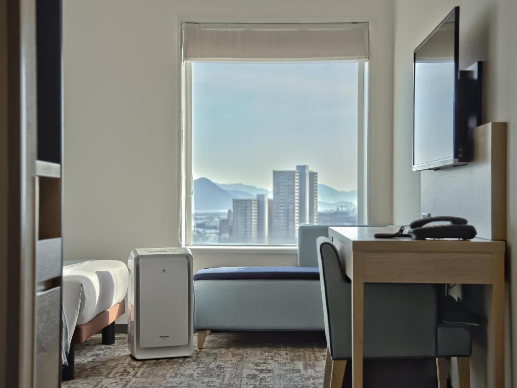a hotel room with a bed and a window at Mitsui Garden Hotel Hiroshima in Hiroshima