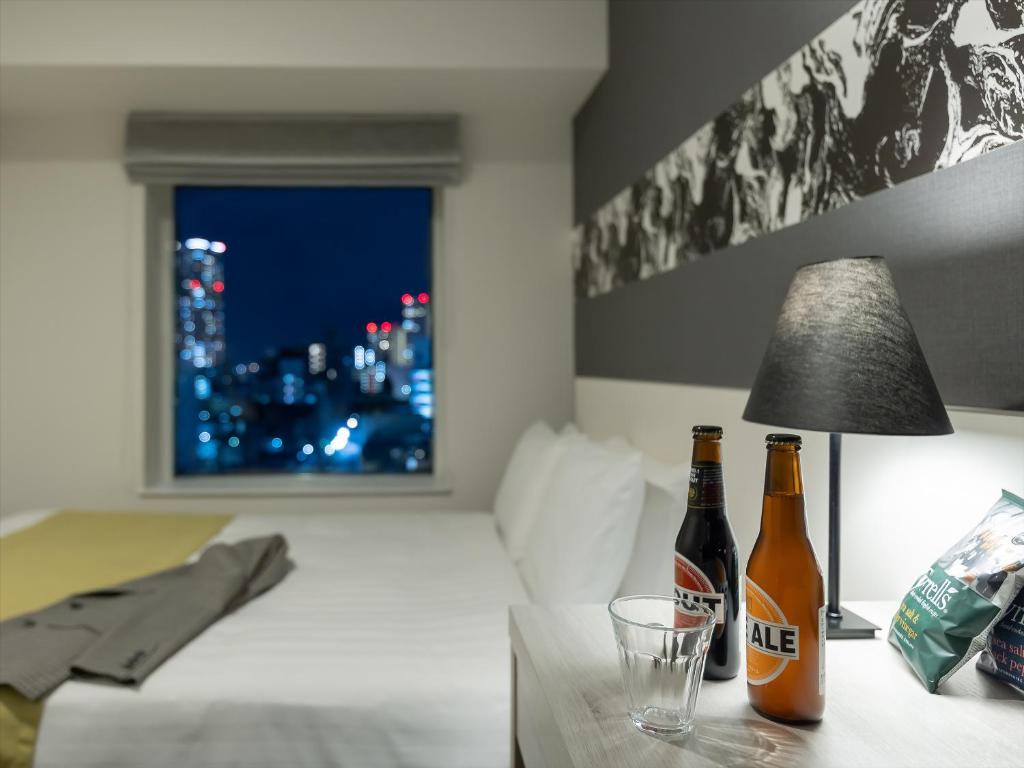 two bottles of beer sitting on a table in a bedroom at Mitsui Garden Hotel Hiroshima in Hiroshima