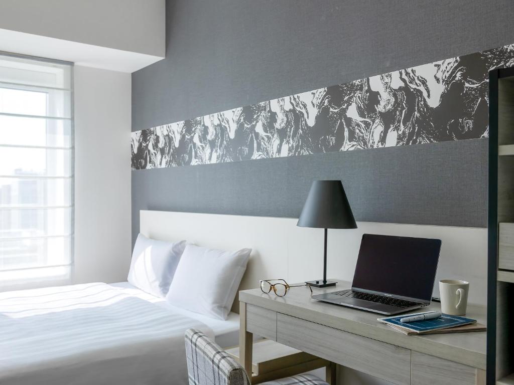 a bedroom with a bed and a desk with a laptop at Mitsui Garden Hotel Hiroshima in Hiroshima