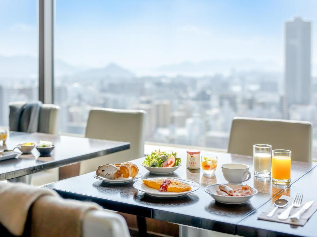 a table with plates of food and drinks on it at Mitsui Garden Hotel Hiroshima in Hiroshima