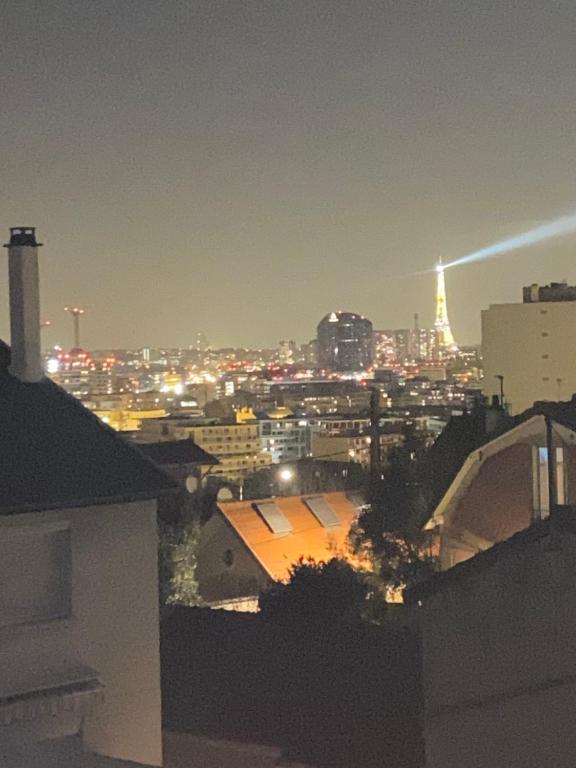 a city skyline at night with the eiffel tower at Appartement proche PARIS in Clamart