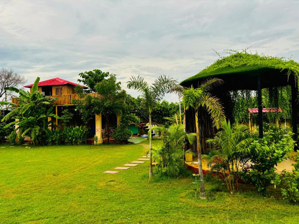 a house with a lush green yard with a building at Aranyaa Cottage Homestay Vrindavan in Jait