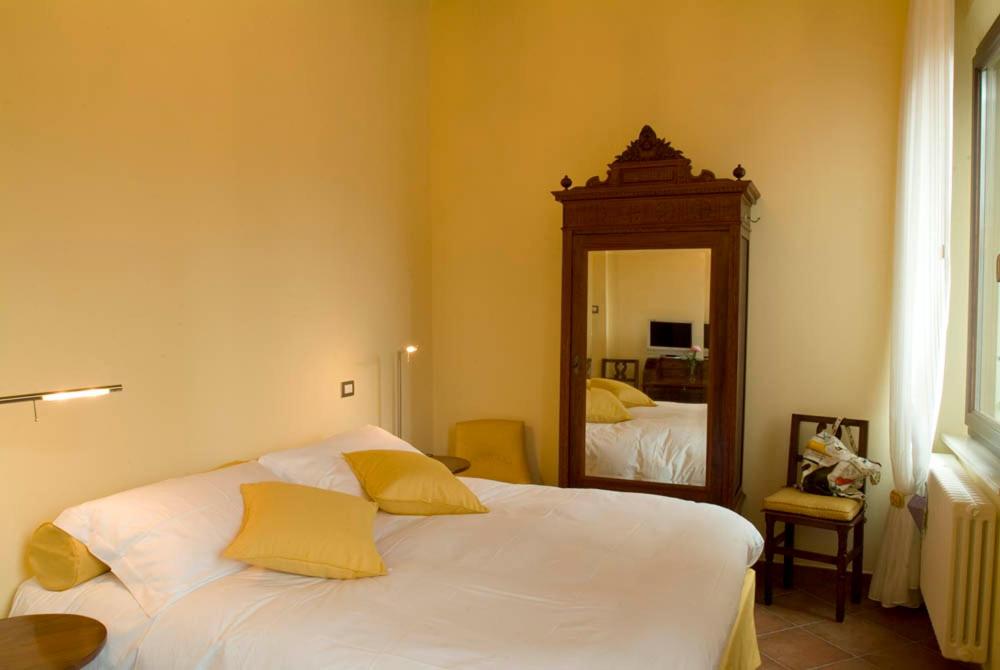 a bedroom with a bed with yellow pillows and a mirror at Ada B&B in Ferrara