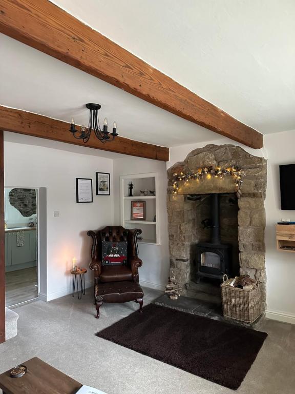 a living room with a stone fireplace and a chair at Ladybird Cottage in Barrowford