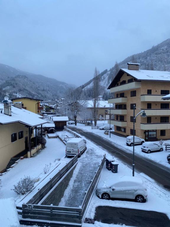 een besneeuwde straat met geparkeerde auto's en een gebouw bij Bellaria Apartment Mountain View in Predazzo