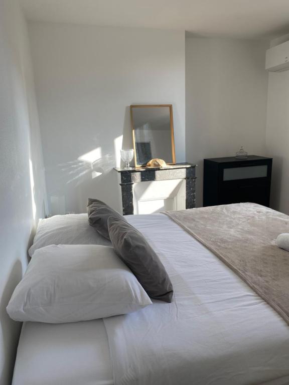 une chambre avec un lit blanc avec des oreillers et un miroir dans l'établissement Maison de charme neuf hyper centre Bordeaux, à Bordeaux