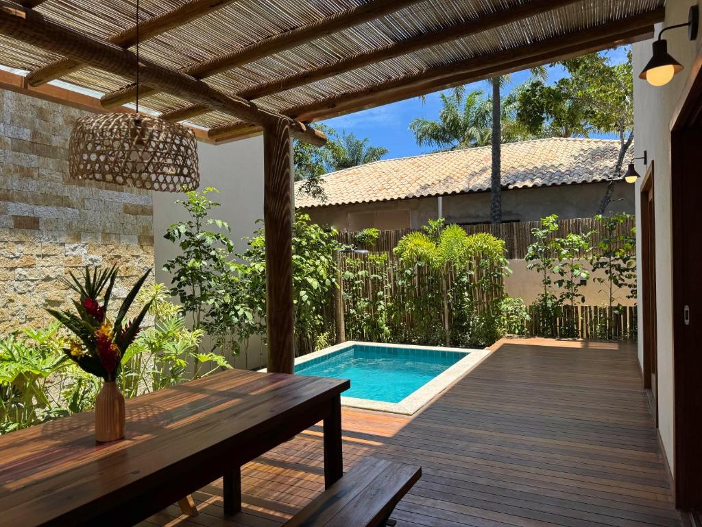a patio with a wooden table and a swimming pool at Bahia Soul - Vilas de Maré - Taipu de Fora - Península de Maraú in Marau