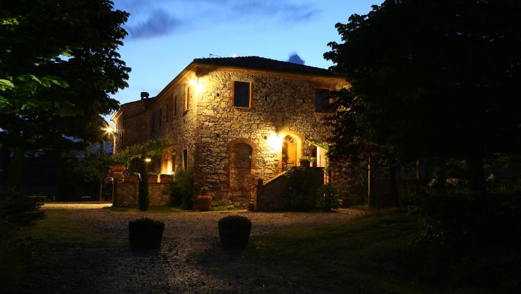 una casa de piedra con luces encendidas por la noche en Agriturismo Podere Alberese, en Asciano