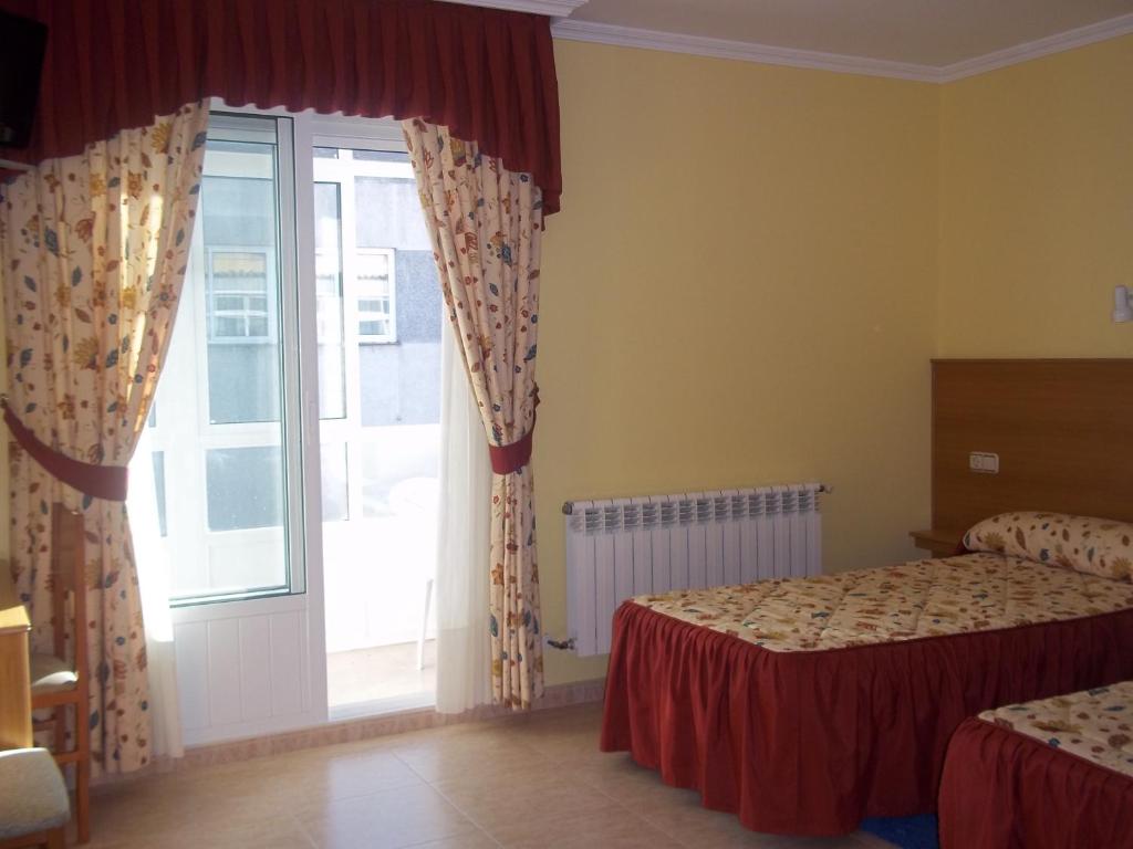a bedroom with two beds and a large window at Hotel Suiza in Arzúa