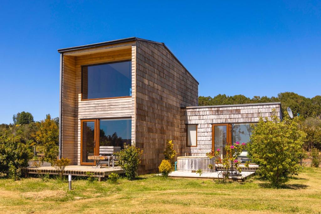 a brick house with benches in a yard at Cabañas Arrayanes de Huillinco en Chiloé in Chonchi