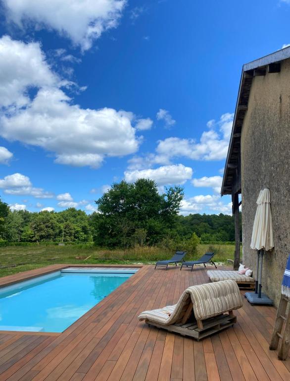 une terrasse en bois avec une piscine et des chaises. dans l'établissement Château Batsères, à Landiras