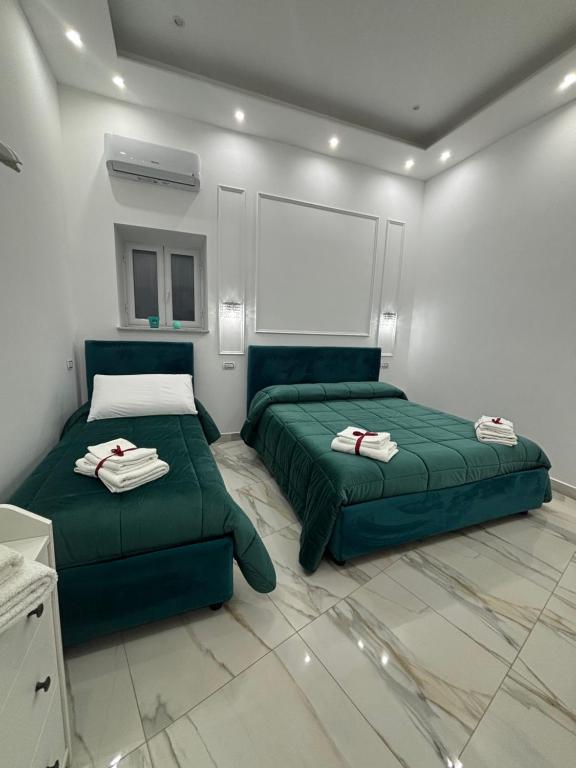 een slaapkamer met twee groene bedden en een witte muur bij Marghe Luxury Home in Napels