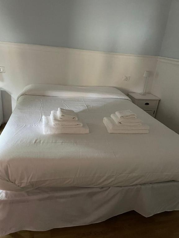 a white bed with two folded towels on it at The First Colombo Brignole XX Settembre in Genoa