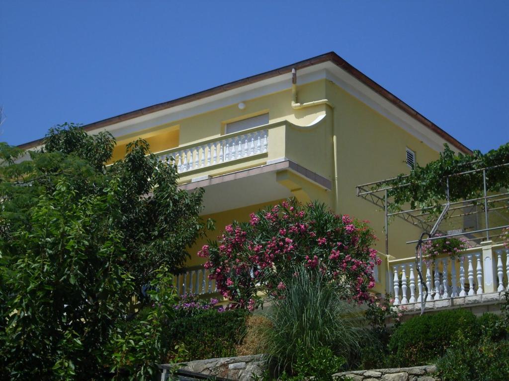 a yellow house with a balcony with pink flowers at Rooms Neda in Rab