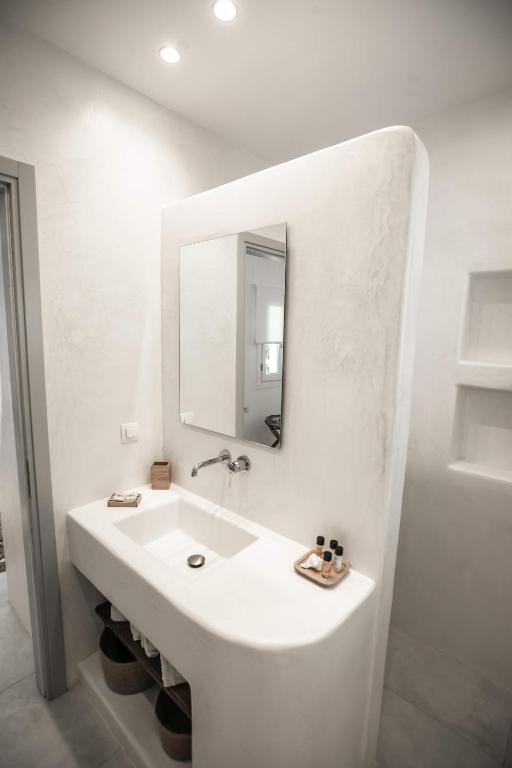 a white bathroom with a sink and a mirror at Ios Art Suites in Ios Chora