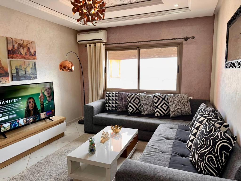 a living room with a couch and a tv at Luxury Appartement Centre-ville Kenitra Netflix & IPTV in Kenitra