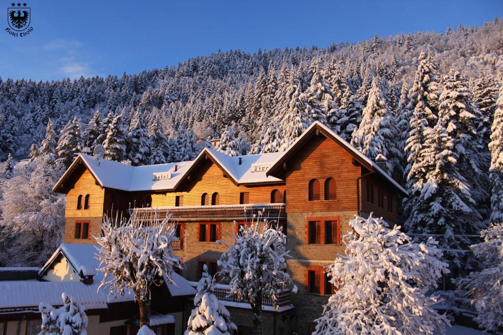 uma casa de madeira nas montanhas com árvores cobertas de neve em Hotel Tirolo em Sestola