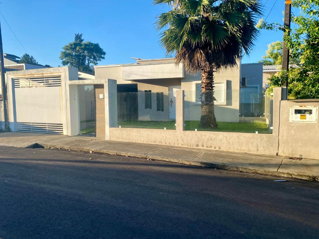a house with a palm tree on the side of a street at Casa térrea para família no centro de Ametista! in Ametista do Sul