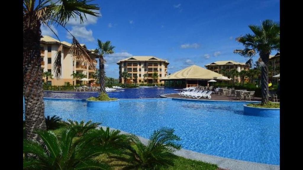 a large swimming pool with palm trees and buildings at VG Sun Cumbuco in Cumbuco