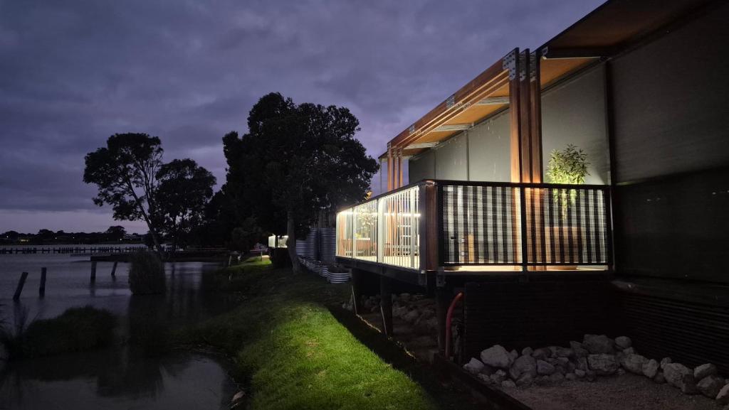 a house with lights on the side of a river at Lake Wellington Luxury Retreat in Wellington East