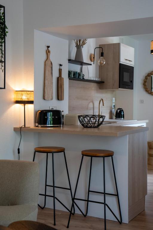 une cuisine avec un comptoir et deux tabourets de bar dans l'établissement Dijon hypercentre - Loge Comédie, à Dijon