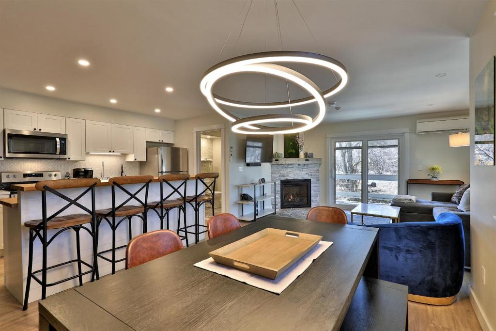 a kitchen and living room with a table and a chandelier at The Swirl Suite, Renovated 2RM-2BA Condo, Sleeps 6, Fireplace, Summer Pool in Killington