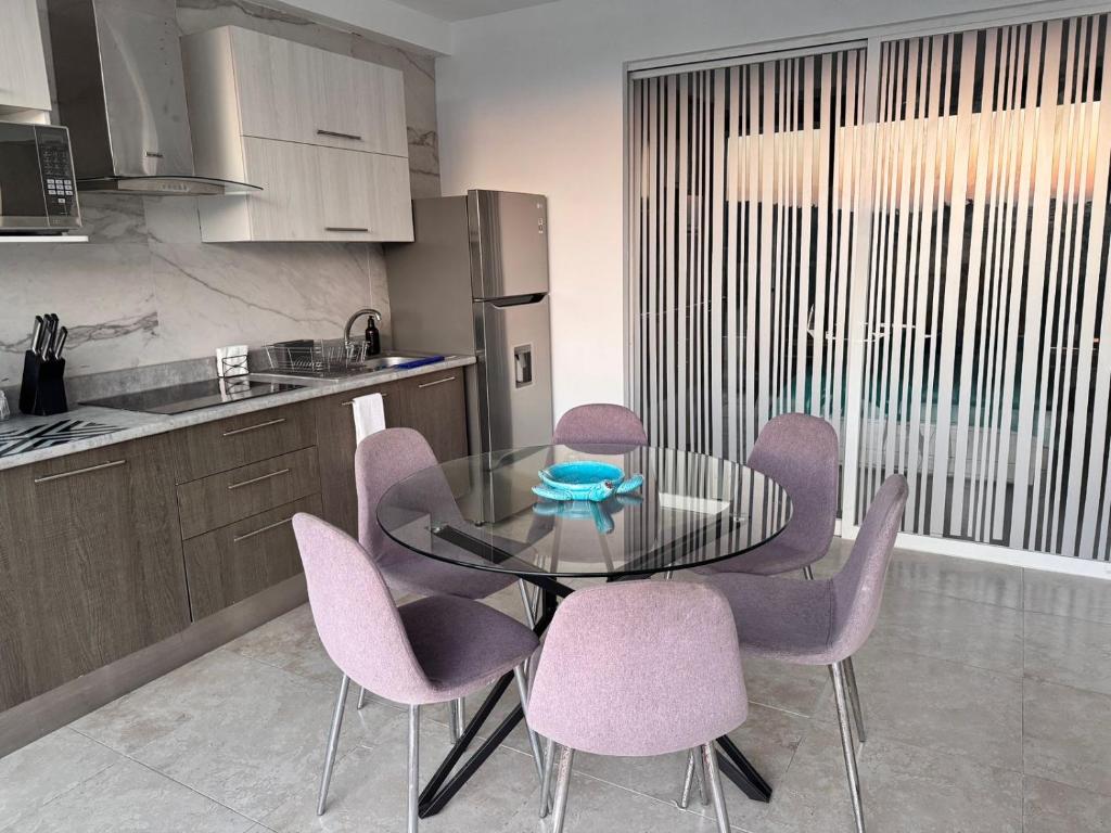 a kitchen with a glass table and purple chairs at Apartamento Blue Acapulco Diamante in Acapulco