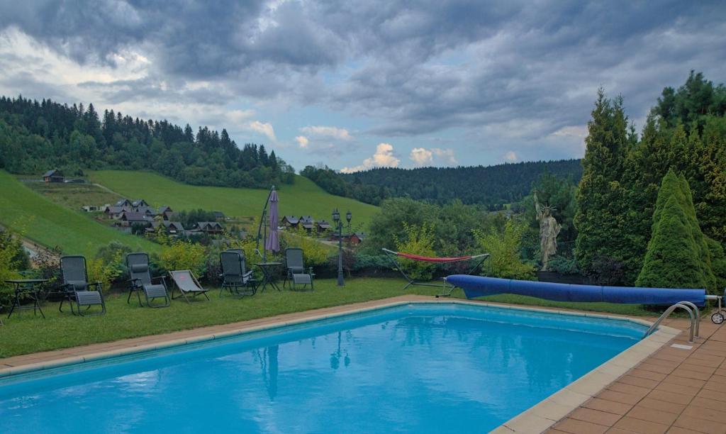 a swimming pool in a yard with chairs and a hill at Willa Wuja Sama in Zawóz