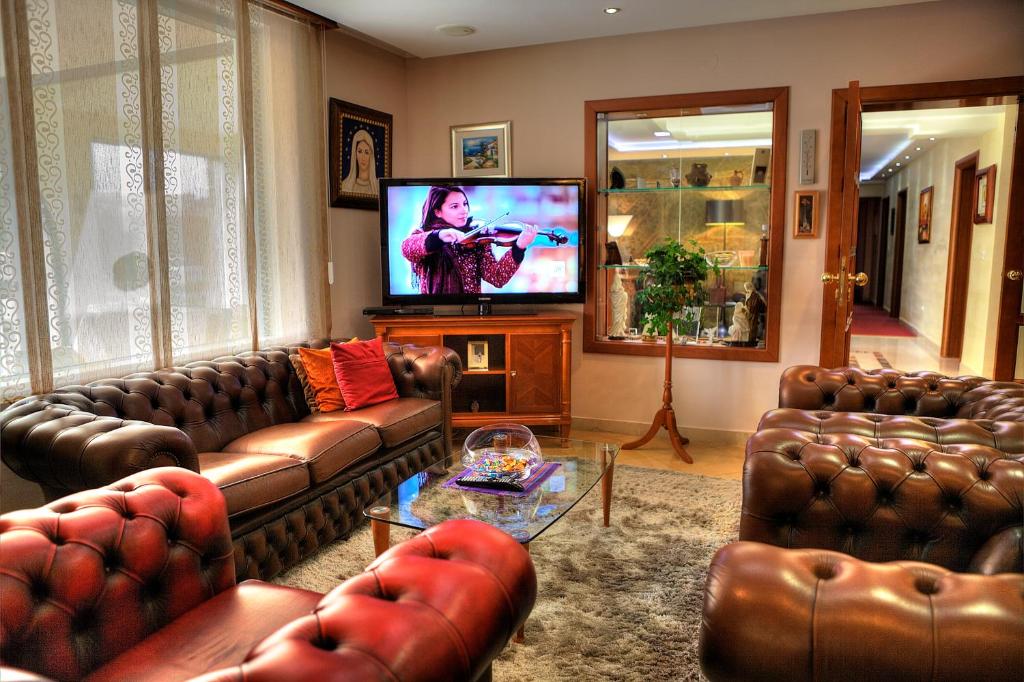 sala de estar con sofás de cuero y TV de pantalla plana en Boutique Hotel Sulić, en Međugorje