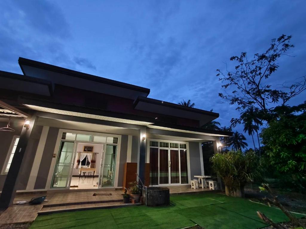 a house with a green lawn in front of it at BaanRatsitornHomestay in Langu