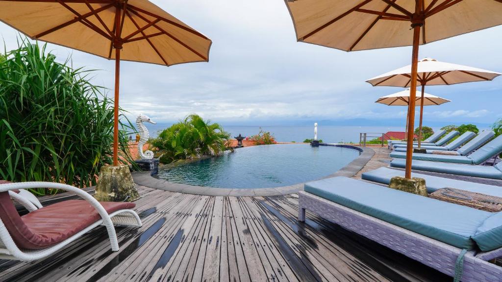 een zwembad met stoelen en parasols op een terras bij Bali Belva in Nusa Lembongan