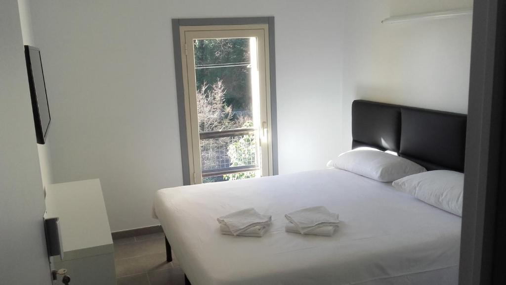 a white bed with two pillows on it with a window at Le Relais de Monti in Menton