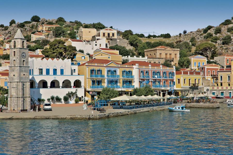 a town with a clock tower next to the water at Nireus Hotel in Symi