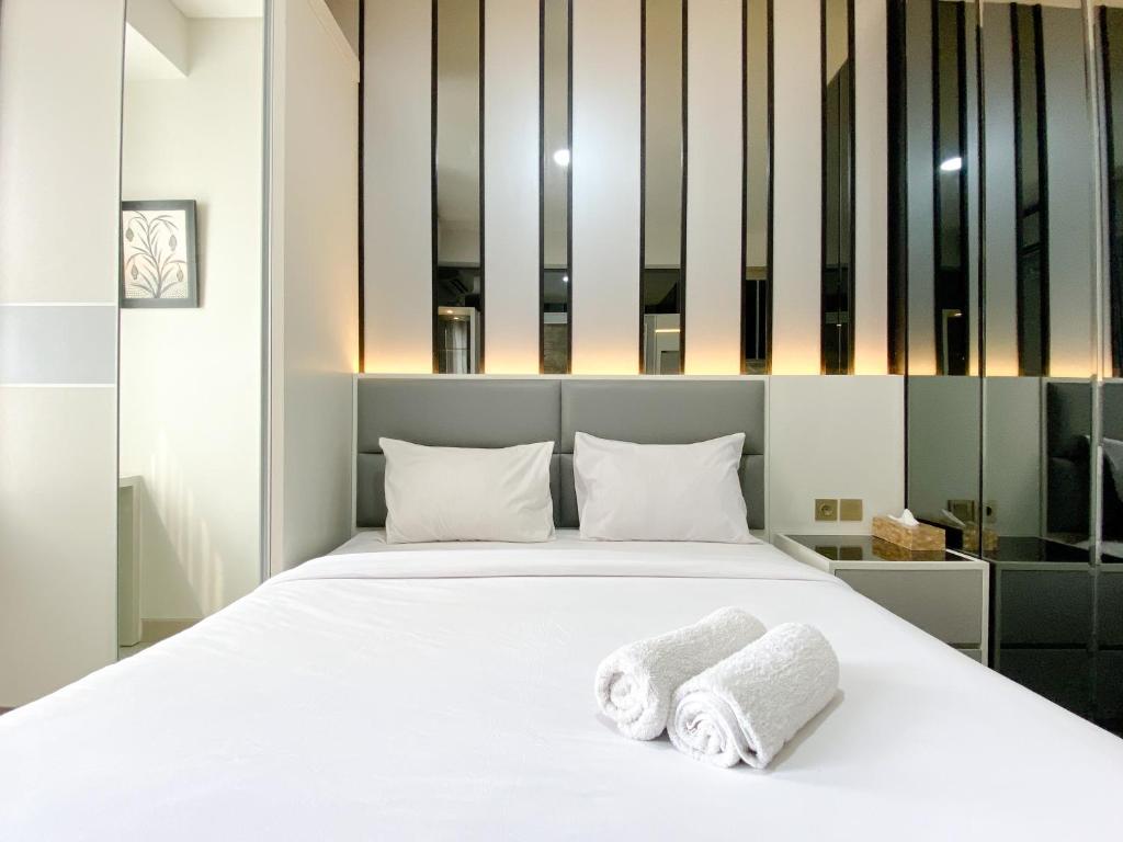 a bedroom with a white bed with towels on it at Best Deal and Cozy Studio Room Transpark Cibubur Apartment By Travelio in Depok