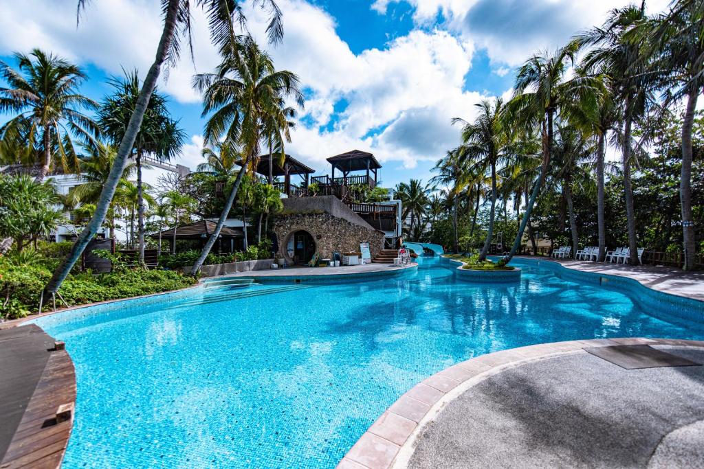 a pool at a resort with palm trees at Yoho Beach Resort Kenting in Hengchun