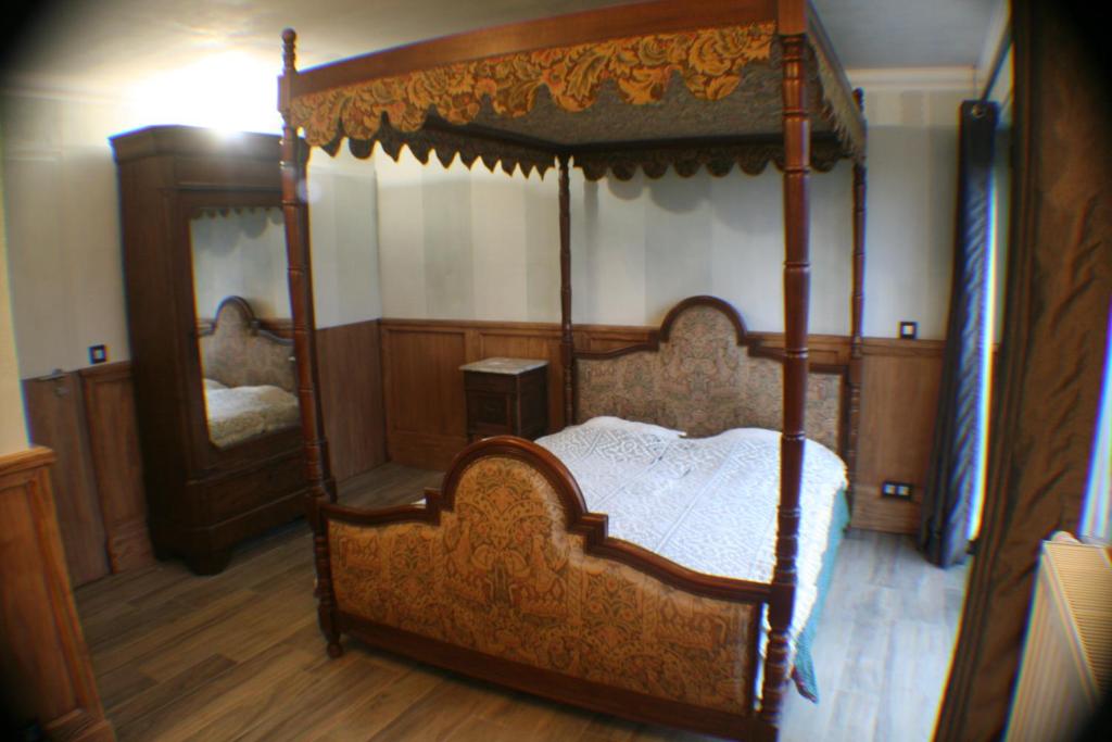 a bedroom with a canopy bed and a mirror at B&B Le Relais de Charlinette in Boignée