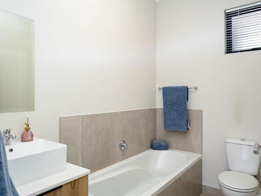 a bathroom with a tub and a toilet and a sink at Sunset Haven in Midrand