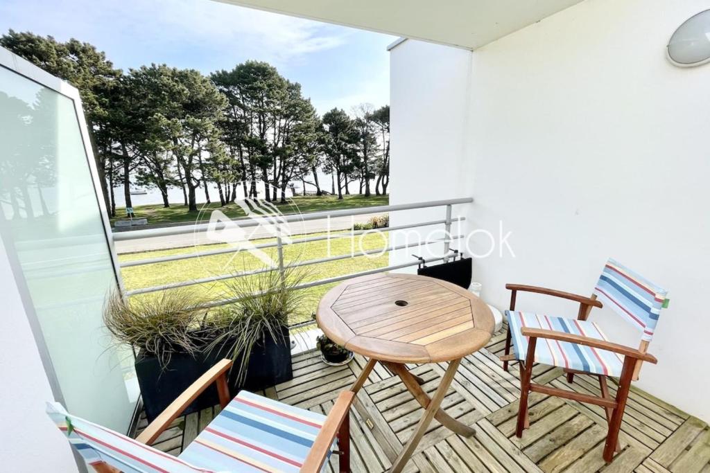 d'un balcon avec deux chaises et une table en bois. dans l'établissement Charmant T2 Top Cosy Face à la rade, à Larmor-Plage
