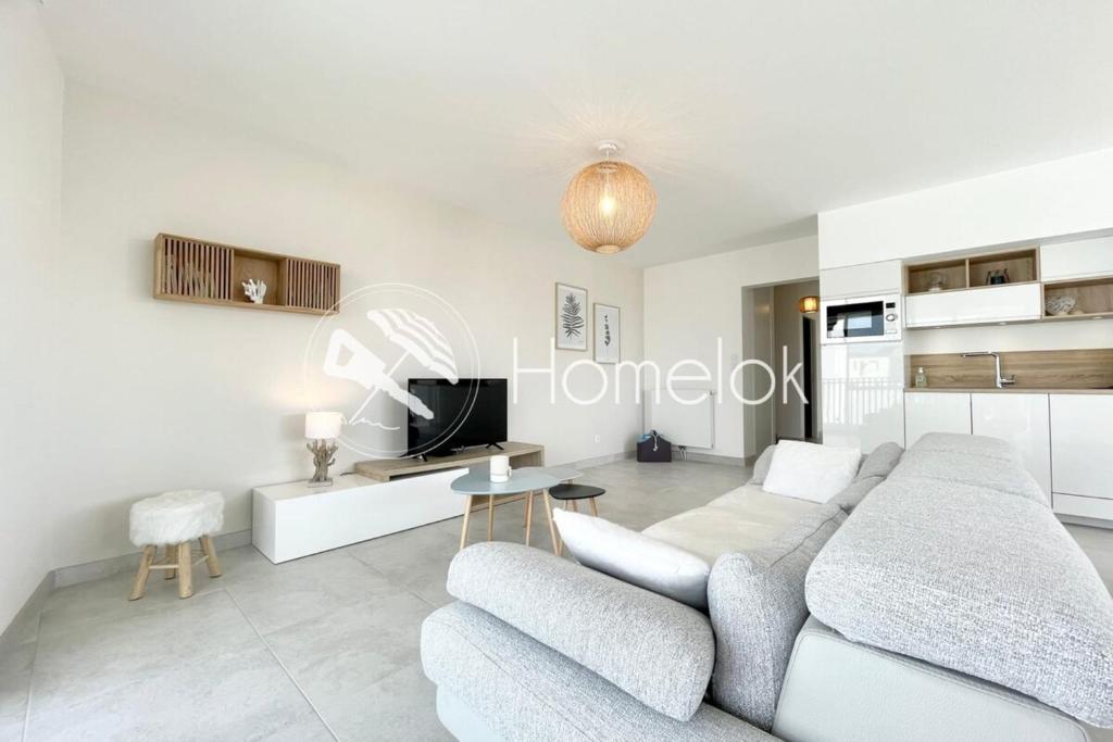 un salon avec un canapé et une télévision dans l'établissement Spacieux appartement neuf de standing Hyper Cosy, à Larmor-Plage