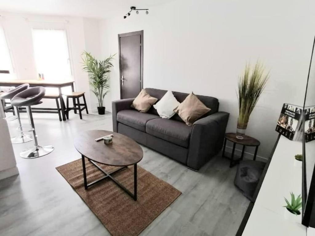 een woonkamer met een bank en een tafel bij Astérix- CDG Aéroport de Paris - Parc expos Villepinte in Louvres