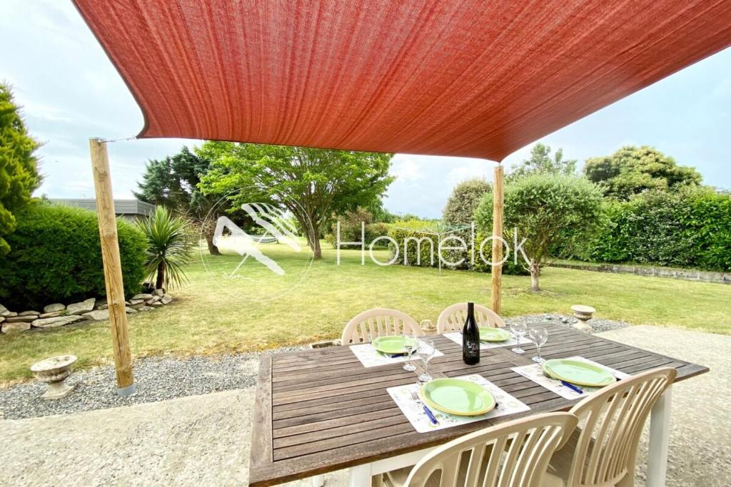 une table en bois avec des chaises blanches et un parapluie rouge dans l'établissement Jolie maison récente confort Proche des plages, à Riantec