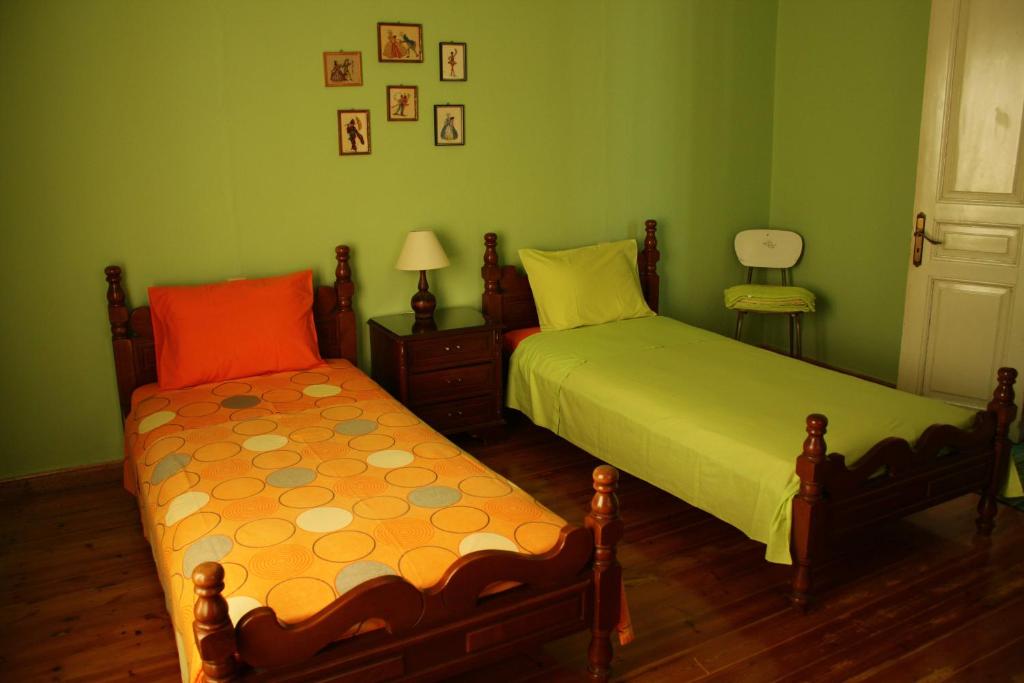 two beds in a bedroom with green walls and wooden floors at Kyra Vintage House in Chania